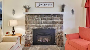 Un salón acogedor con chimenea de piedra, un sofá, una lámpara y adornos en la repisa.
