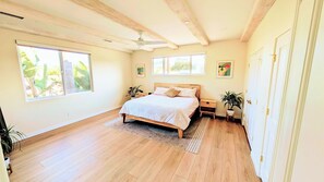 Une chambre spacieuse dotée d’un grand lit, d’un plancher en bois et de nombreuses fenêtres qui laissent entrer la lumière naturelle.