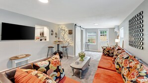 A modern living room with a sofa set, a coffee table, and a flat-screen TV mounted on the wall.