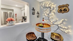A modern kitchen with a stainless steel refrigerator, a white countertop, and a wooden dining table with a decorative centerpiece.