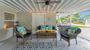 A covered patio with wicker furniture, a ceiling fan, and a view of the backyard.