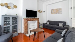 A modern living room with a fireplace, grey sofa, and a cabinet with glass doors.