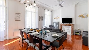 A dining area with a table set for four, a grey sofa, a television, and a fireplace.