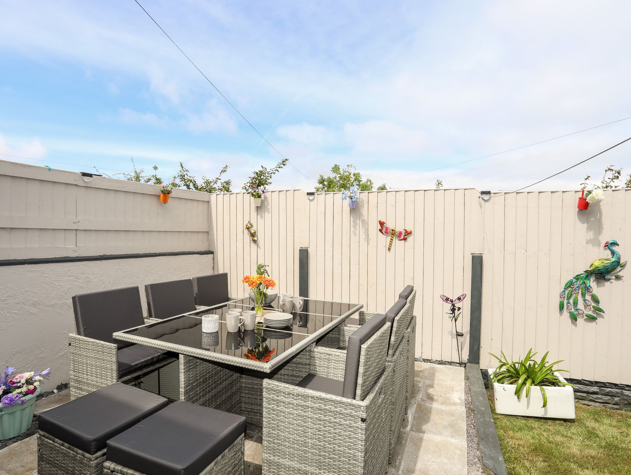 A patio area with wicker furniture, a glass-top table, and potted plants.