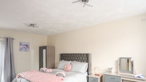 Ein Schlafzimmer mit einem Bett, Nachttischen, einem Schreibtisch und einem Deckenventilator.
