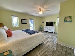 A bedroom with a bed, a dresser, a television, and a ceiling fan.