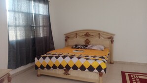 A bed with a patterned bedspread, a headboard with decorative elements, and a window with a curtain.