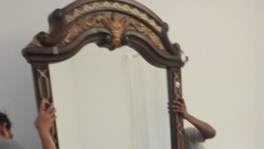 A room with a wooden dresser, a mirror, and a bed with a floral bedspread.
