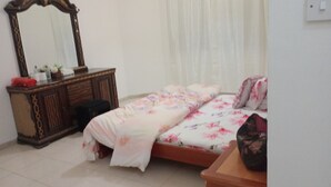 A bedroom with a bed, a dresser, a mirror, and a window with curtains.
