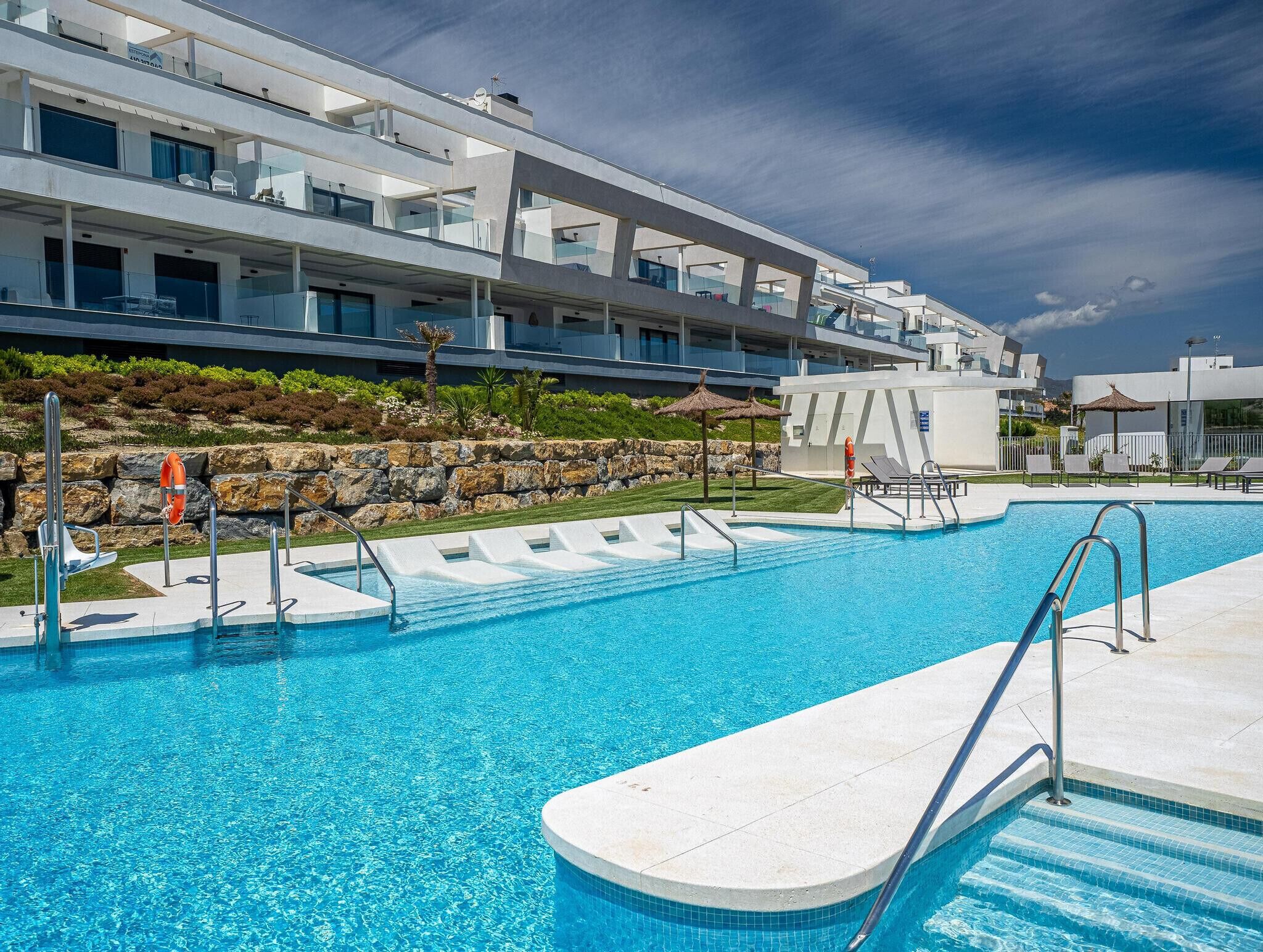 Un hotel moderno con piscina, asientos al aire libre y un paisaje rocoso.