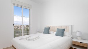 Une chambre à coucher avec un lit, deux oreillers, une table de chevet, une lampe et une vue par la fenêtre.