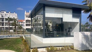 Ein modernes Gebäude mit Glasfassade, Balkon und Poolbereich.