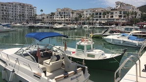 A marina with boats docked, a blue canopy, and buildings in the background. - Punta Paloma Penthouse 2364 Sea View (Manilva)