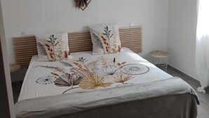 Une chambre avec un grand lit, deux éléments de décoration murale, une lampe suspendue et une petite table d’appoint.
