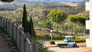 Ein Parkplatz mit einem blauen Lkw, einem Wegweiser und Blick auf eine hügelige Landschaft.