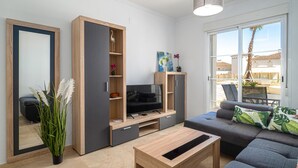 Ein modernes Wohnzimmer mit Sofa, Fernseher und offener Regaleinrichtung.