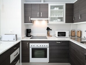 A modern kitchen with dark wood cabinets, a built-in microwave, a toaster, and a coffee maker.