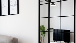 En moderne stue med en grå sofa, et hvidt bord og et stort vindue med sort ramme.
