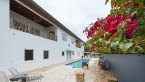 A poolside area with a white building, outdoor furniture, and a flower wall. - Light, Bright and Full of Delight! 2 Blocks to Park Ave (Winter Park)