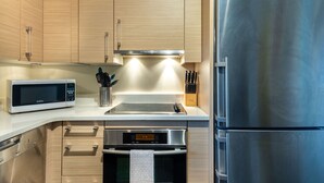 A modern kitchen with stainless steel appliances, wooden cabinets, and a built-in oven. - Light, Bright and Full of Delight! 2 Blocks to Park Ave (Winter Park)