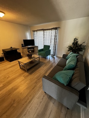 Relax in this stylish living room with a flat-screen TV, comfortable sofa, and a cozy armchair.
