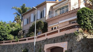 A villa with a stone facade, a large entrance gate, and a balcony with railings. - BEAUTIFUL 3-ROOM APARTMENT WITH SEA VIEW - LES ISSAMBRES (Roquebrune-sur-Argens)
