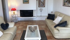 A living room with a fireplace, two sofas, a coffee table, and a lamp. - BEAUTIFUL 3-ROOM APARTMENT WITH SEA VIEW - LES ISSAMBRES (Roquebrune-sur-Argens)