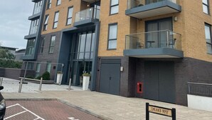 A multi-story residential building with balconies, a garage, and a parking area. - Impeccable 2-bed Apartment in Reading (Reading)