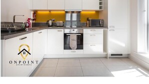 A modern kitchen with white cabinets, a stainless steel range hood, and a microwave. - Impeccable 2-bed Apartment in Reading (Reading)