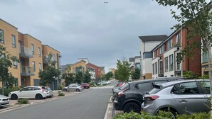 A residential street lined with modern apartment buildings, parked cars, and well-maintained greenery. - Impeccable 2-bed Apartment in Reading (Reading)