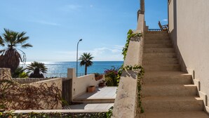 A staircase leading to a balcony overlooking the sea, with palm trees and potted plants. - Apartment (Marina di Ragusa)