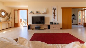A modern living room with a flat-screen TV, wooden furniture, and a red rug. - Apartment (Marina di Ragusa)