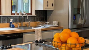 Eine moderne Küche mit Gaskochfeld, Edelstahlgeräten und einer Schale Orangen auf der Arbeitsfläche.