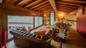 Ein geräumiges Wohnzimmer mit einer Ledersofa, Holzboden und Blick auf ein Gebäude aus Stein.