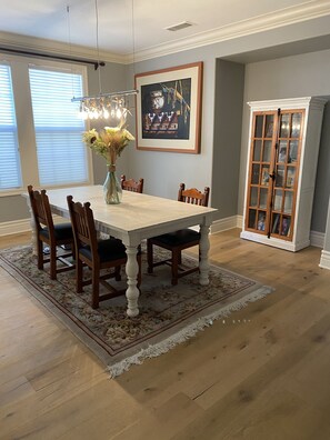 Enjoy meals in this dining area with a large window, a chandelier, and a wooden cabinet.