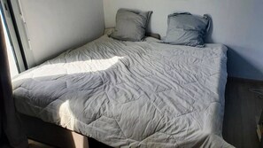 Ein Bett mit einer gesteppten Tagesdecke und zwei Kissen.
