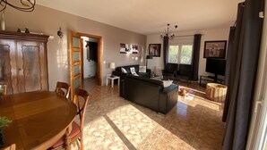 A spacious living room with a dining area, a sofa set, a TV, and a chandelier. - Weekly rental, villa Lloret de Mar with private pool, quiet area (Lloret de Mar)