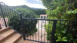A staircase leading to a covered outdoor area with a metal railing, surrounded by greenery and a view of a building in the distance. - Weekly rental, villa Lloret de Mar with private pool, quiet area (Lloret de Mar)