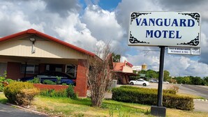 A motel named 'Vanguard Motel' with a signboard, a parking area, and a building with a red roof. - Vanguard Motel (Navasota)