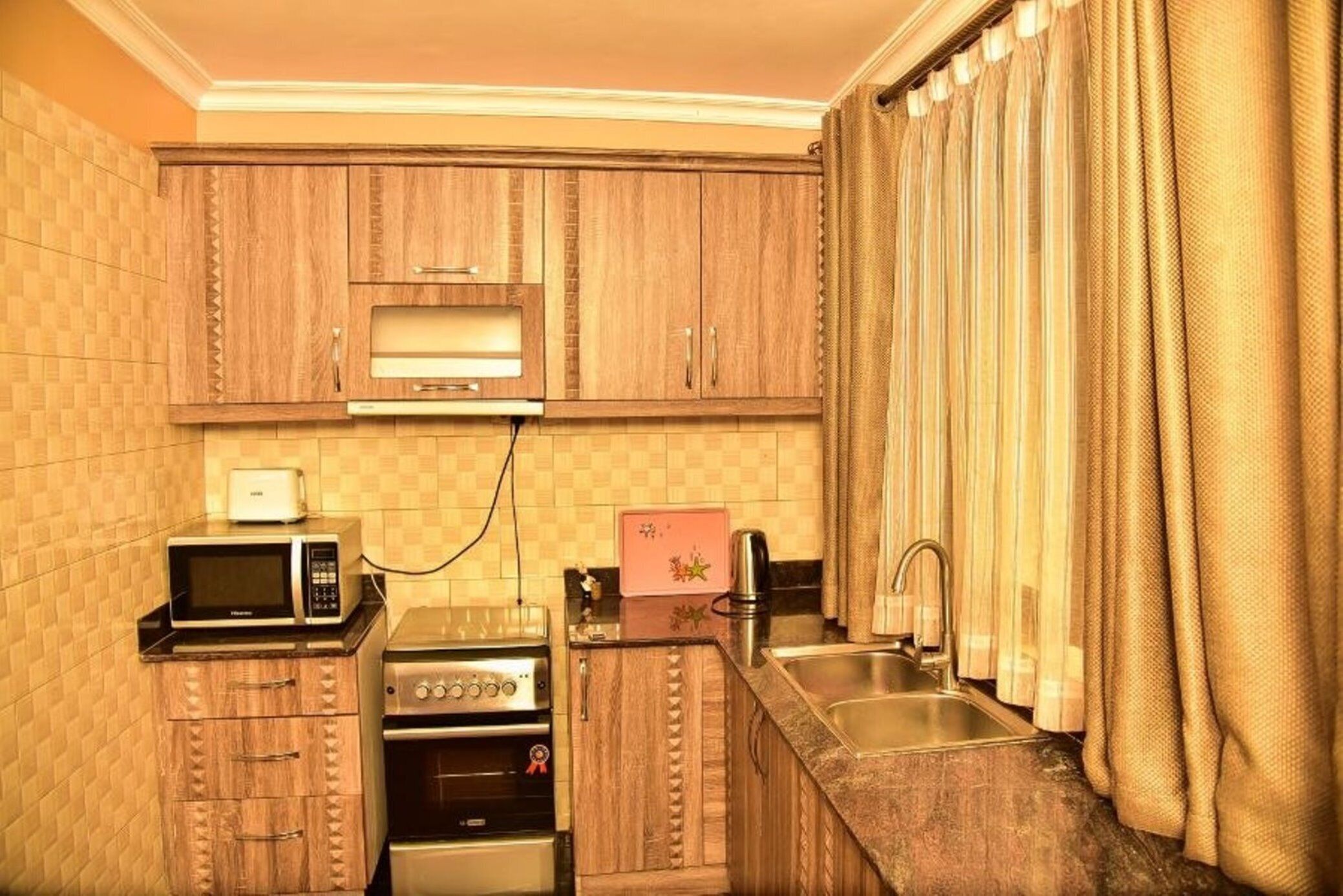 A compact kitchen with wooden cabinets, a microwave, a toaster, and a sink.