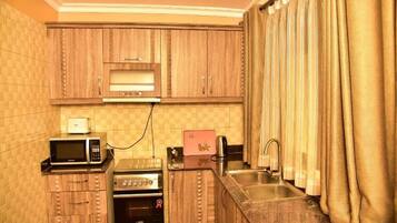 A compact kitchen with wooden cabinets, a microwave, a toaster, and a sink.
