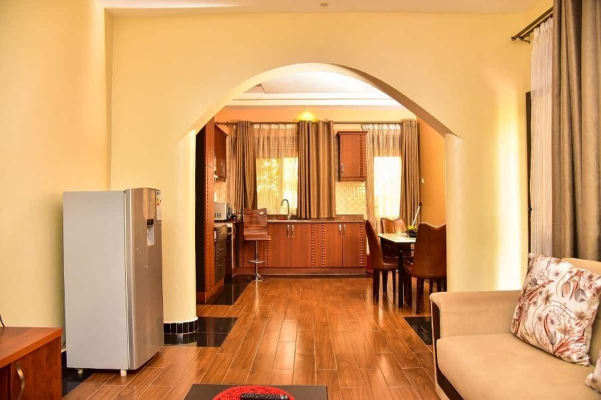 Sala de estar con un sofá y comedor con mesa y sillas. Se ve una cocina a través de un arco.