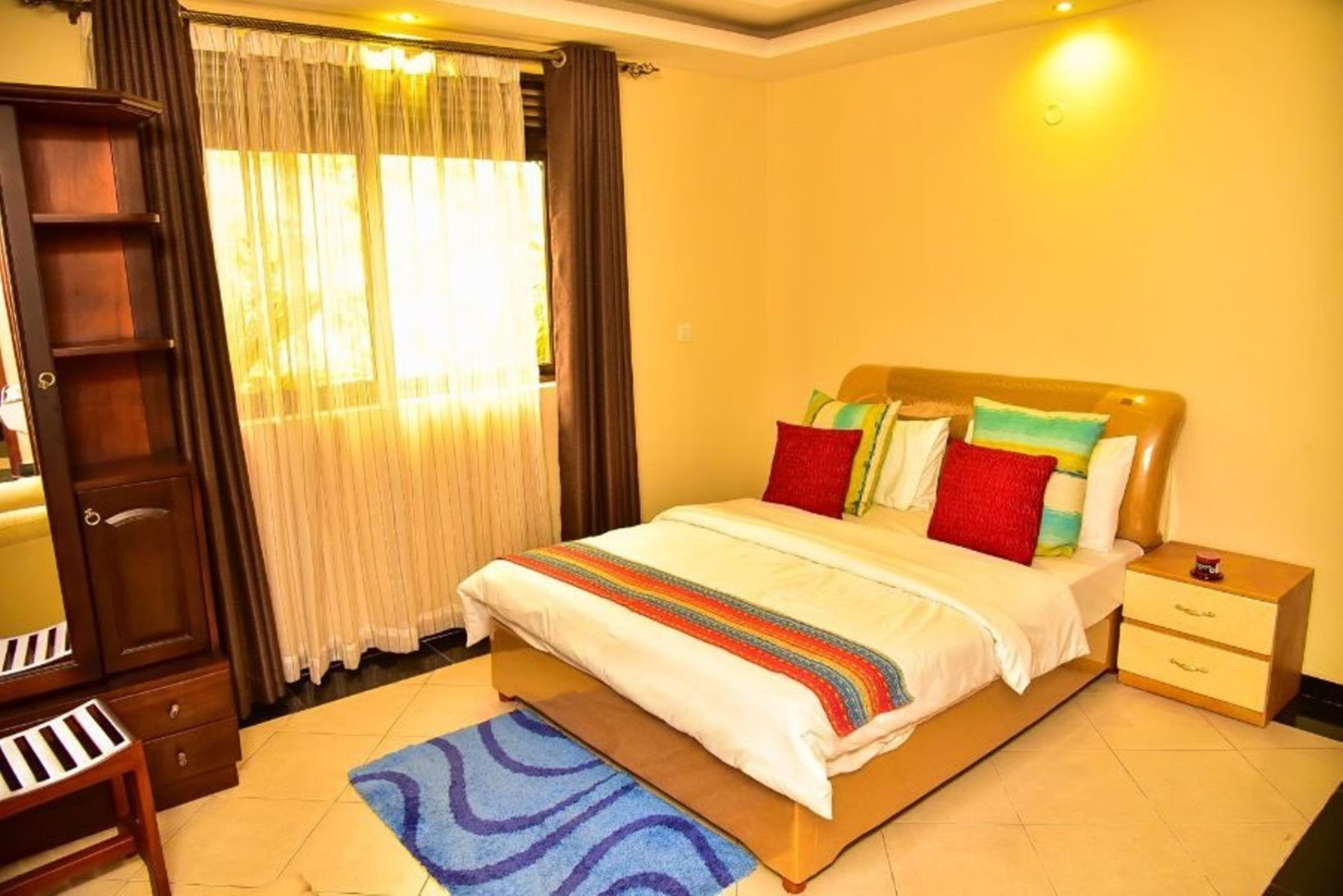 A neatly arranged bedroom with a bed, bedside tables, a wardrobe, and a desk.