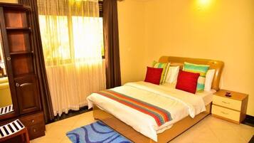 A neatly arranged bedroom with a bed, bedside tables, a wardrobe, and a desk.