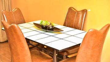 A dining table with a tiled top, surrounded by four brown leather chairs.