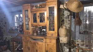Une pièce au décor rustique, meublée de meubles en bois, notamment un meuble avec des portes en verre et un grand panier tressé.