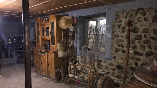 Une pièce rustique avec un mur en pierre, des meubles en bois et une grande fenêtre.
