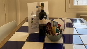 Uma mesa com uma garrafa de vinho, uma tigela de petiscos e um quadro emoldurado.