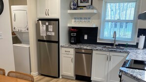 A modern kitchen with white cabinets, stainless steel appliances, and a wooden dining table. - Eagles Nest Cottage in Egg Harbor, Door County, WI (Egg Harbor)