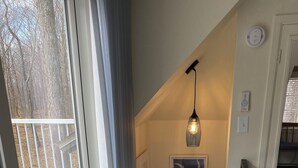 A staircase with a patterned carpet, a hanging pendant light, and framed botanical prints on the wall. - Eagles Nest Cottage in Egg Harbor, Door County, WI (Egg Harbor)